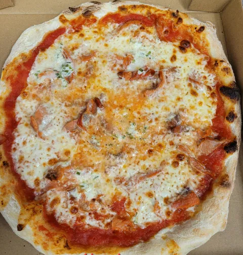 Pizza et sa sauce tomate garnie de saumon et d'une crème a la ciboulette. 