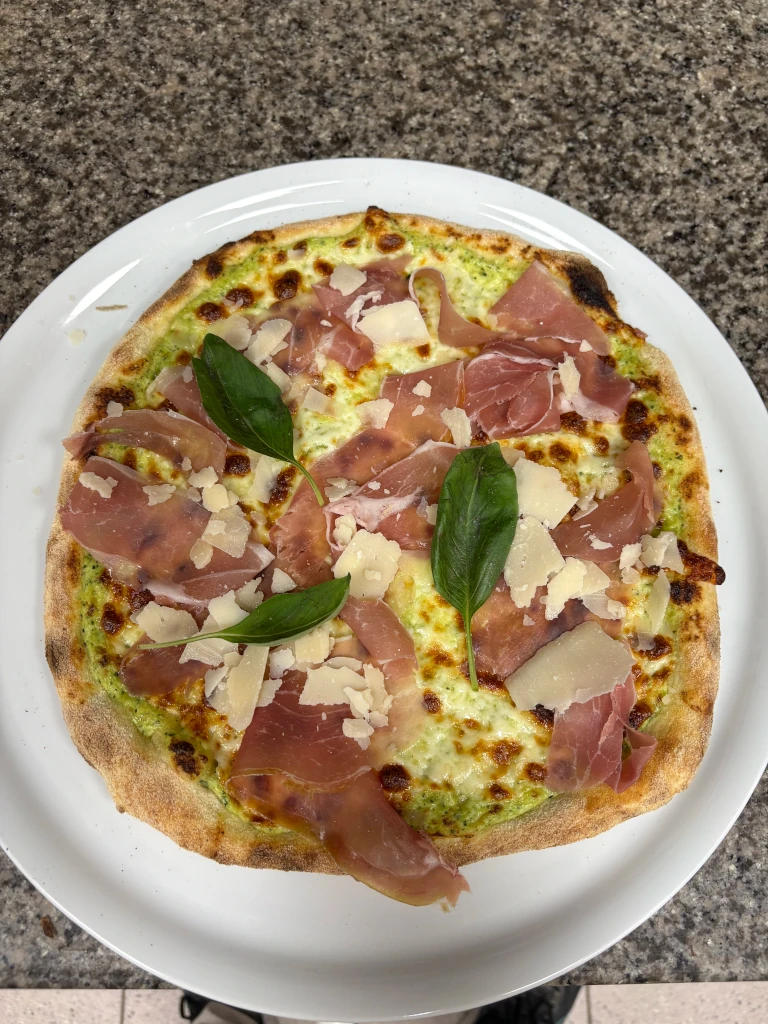 Pizza du moment avec une base crême de courgette et Mozzarella, garni de jambon cru, parmesan et basilic.